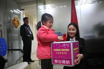 一名5岁的女童将刚拿到的压岁钱放入捐款箱中